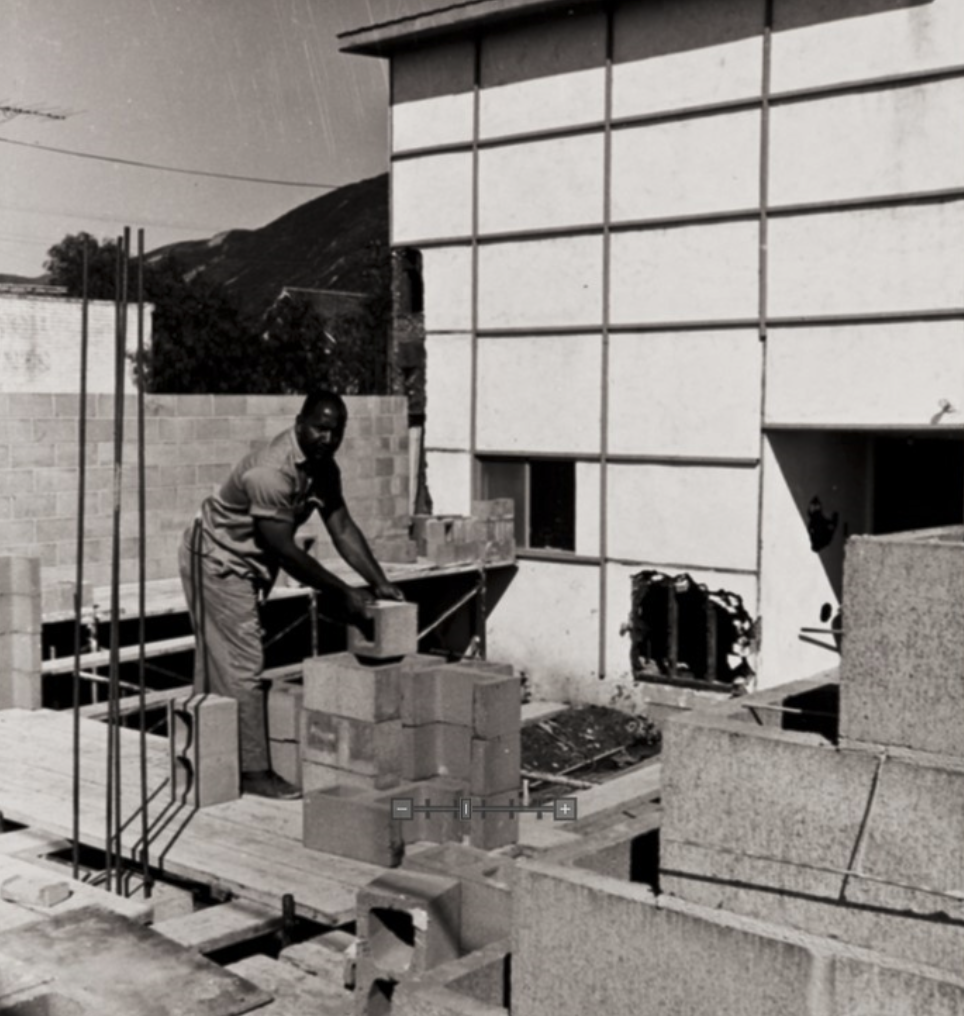 An African American man uses cinder blocks to build the foundation of his church