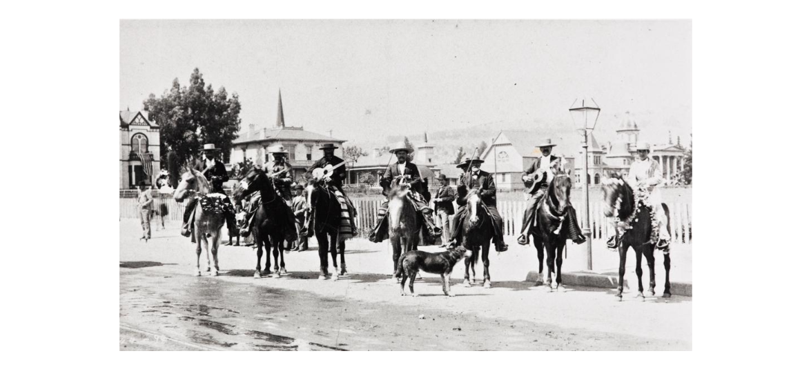 7 musicians on horseback stand in a line with various instruments and regalia